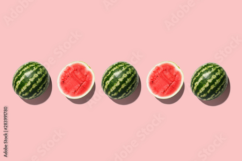 Row of fresh watermelon in center on pink backgrond. Top view