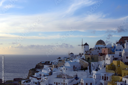 Santorini, Greece, April 2019. White traditional Greek houses on a hillside on the island of Santorini. Tourists are waiting for sunset. Sunset in the city of Oia, Santorini.