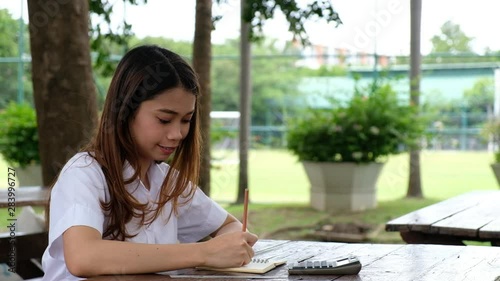 Student woman sitting at table, writing on notepad with pencil, education outdoor concept
