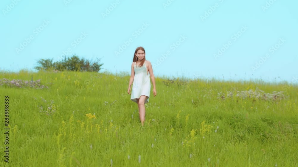 Cheerful smiling little girl in trendy summer dress enjoying nature, walking down the meadow through blooming high-grass. Joyful mood, excitement, adventure time. Nature lover concept Cheerful smiling little girl in trendy summer dress enjoying nature, walking down the meadow through blooming high-grass. Joyful mood, excitement, adventure time. Nature lover concept