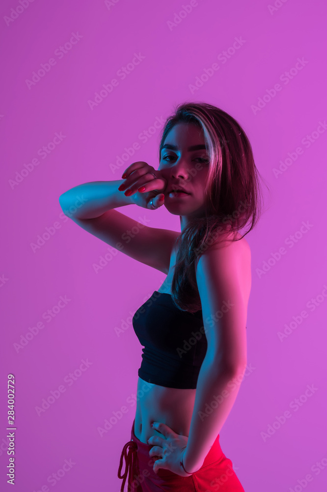 Young pretty woman possing while standing isolated on pink light background Young pretty woman possing while standing isolated on pink light background