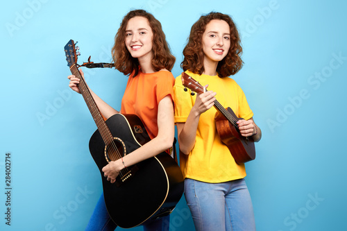 gorgeous band going to take part in the consert, twins preparing for a performance, close up photo. isolated blue background photo