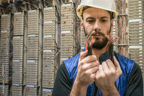 Engineer will connect damaged Internet backbone wire. Worker restores the connection in the data center server room. Technician holds in his hands the two ends of torn telephone cable. photo