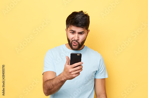 handsome man has recieved strange message, mobile crime. man has lost money, close up portrait, isolated yellow background