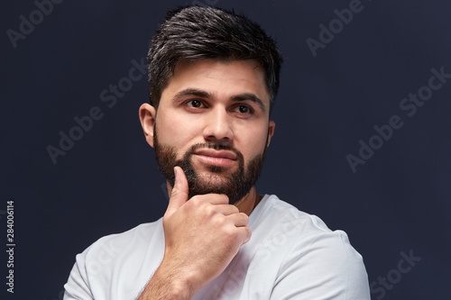 attractive Arab guy thinking about life, problems, looking aside, isolated black background, studio shot, philosophical thinking, reflection, dream concept