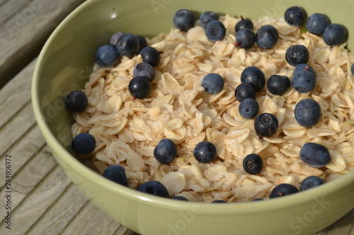 oatmeal with fresh blueberries. organic cereals in the green bowl on the wooden background. vegan breakfast.