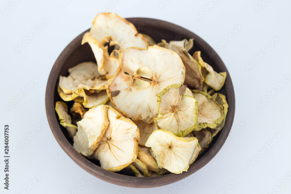 Apple chips in a brown clay bowl isolated