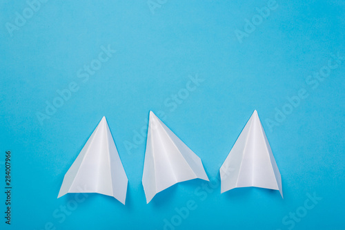 white paper airplane on a navy paper background © Nana_studio
