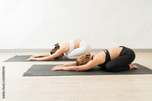 Young Females Practicing Balasana On Mats At Yoga Studio