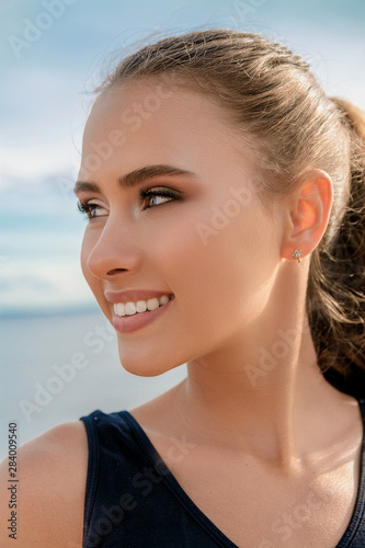 Portrait of a beautiful girl on the beach against the beautiful sky. Girl smiles