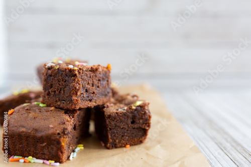 Banana brownies with multi colored sprinkles, crinkled parchment paper, wooden background