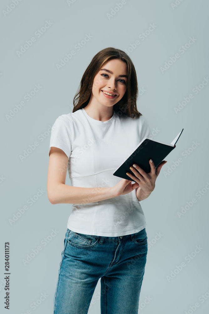 happy beautiful girl in white t-shirt holding notebook isolated on grey happy beautiful girl in white t-shirt holding notebook isolated on grey