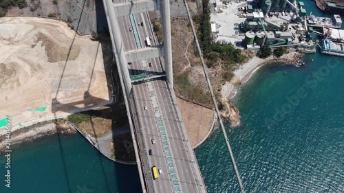 Two legged pylon and road deck of large suspension bridge, top-down aerial shot. Lively traffic at Tsing Ma bridge, part of Lantau Link of Hong Kong. Tower bankseat on reclaimed land photo