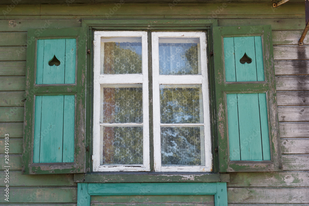 simple window with shutters on a green wooden wall