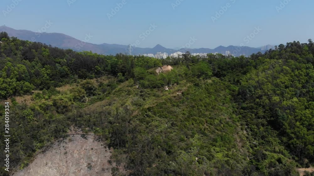 Green hills range at Tsing Yi island, aerial camera fly forward, approaching top of small forested ridge. Popular hiking or trekking area at Hong Kong Green hills range at Tsing Yi island, aerial camera fly forward, approaching top of small forested ridge. Popular hiking or trekking area at Hong Kong