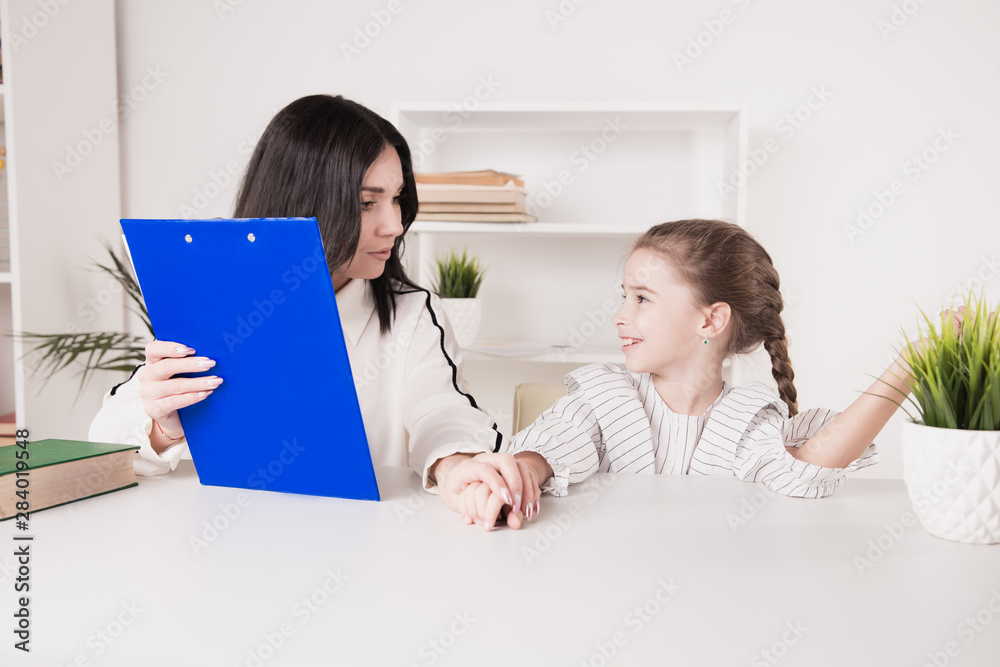 Teacher and litle girl working on a pronunciation together in the class Teacher and litle girl working on a pronunciation together in the class