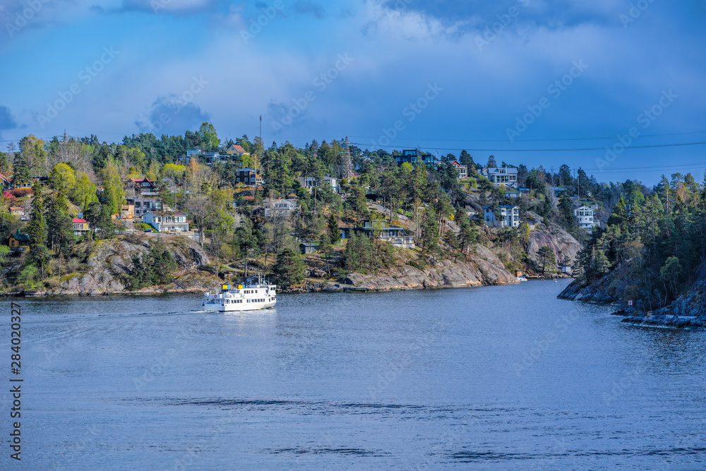 Commuter ferry entering to Skurusundet strait in the Stockholm archipelago at a sunny spring evening.