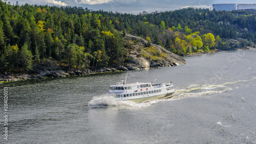 Commuter ferry cuts through the waves in the Stockholm archipelago at a sunny spring evening.