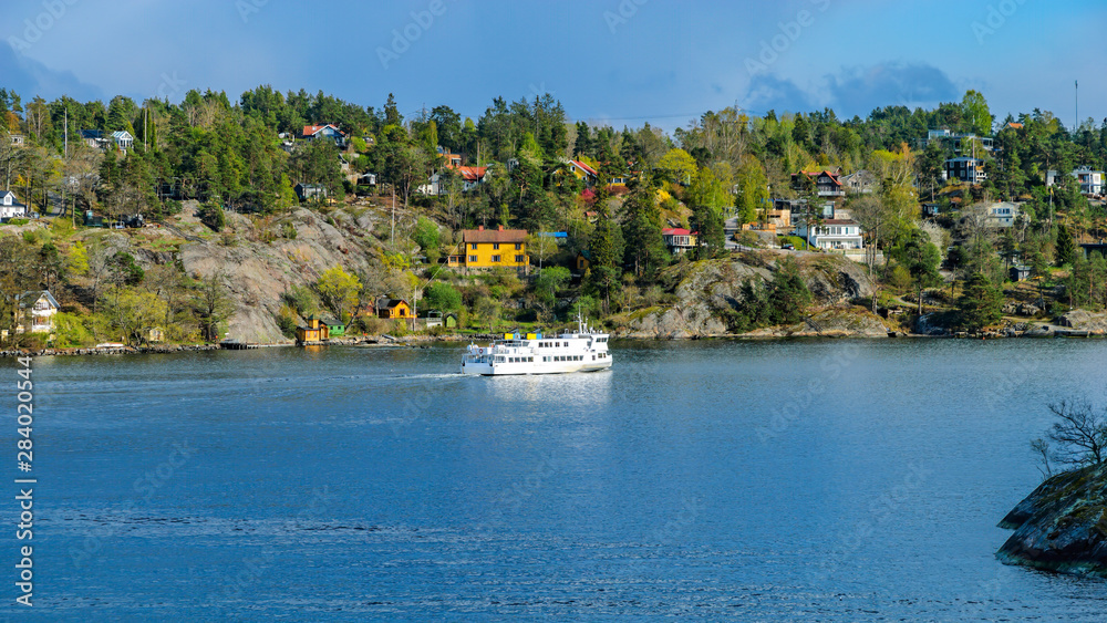 Commuter ferry entering to Skurusundet strait in the Stockholm archipelago at a sunny spring evening.