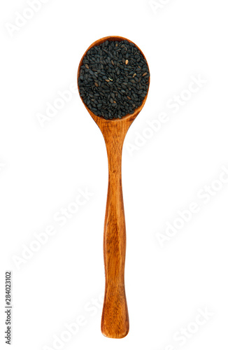 Black sesame seeds in a wooden spoon. View from above. Spices in a spoon. Sugar seasoning.