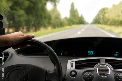 car interior with driver’s hand on the road on a track in rainy weather © Alina