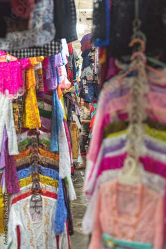 looking down a narrow lane in a clothing market in bali , july 22 2019