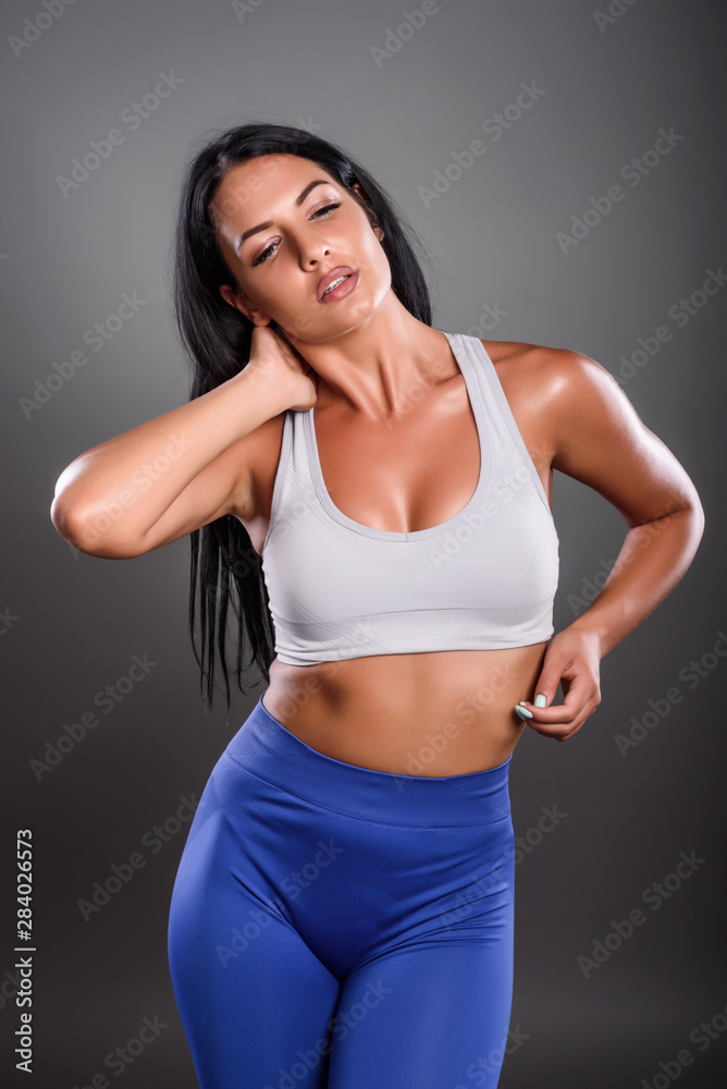 Beautiful young fitness woman. Fitness instructor girl posing in studio. Neck pain. Beautiful young fitness woman. Fitness instructor girl posing in studio. Neck pain.