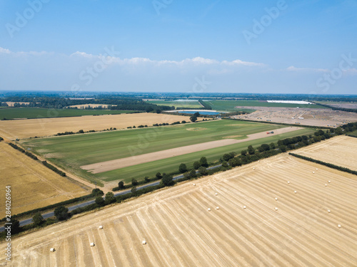 An aerial view of Suffolk farm lands, one field has green crops planted. Another field has hay which has been harvested and baled up