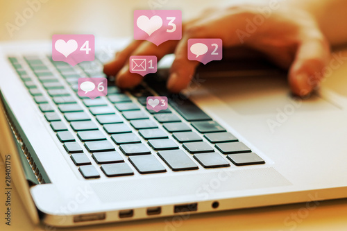 Person is using laptop with black keys, Social media and social networking. Marketing concept. Hearts and letterboxes with counters. Marketing and business concept. May be used for illustration. photo