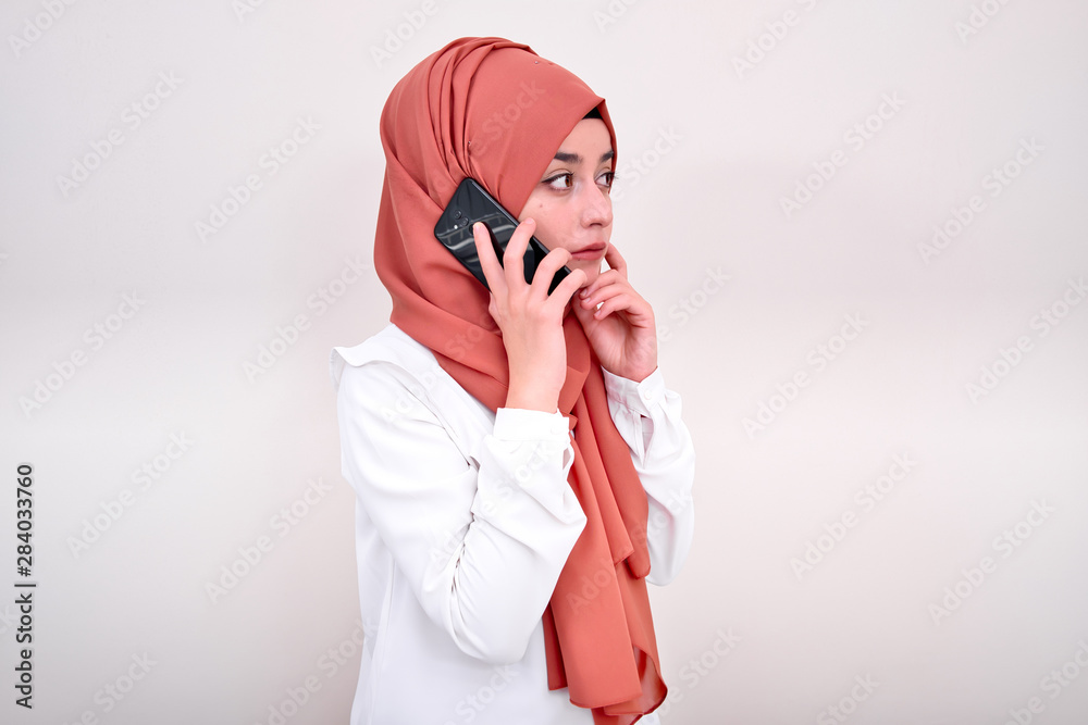 Muslim woman calling, hijab girl standing and calling with mobile phone Muslim woman calling, hijab girl standing and calling with mobile phone