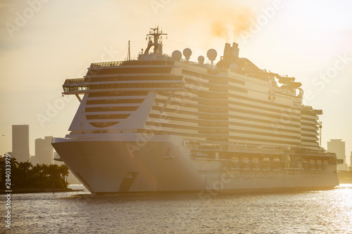 Golden backlit view of putrid brown exhaust smoke billowing from the smokestack of a cruise ship at sunset photo