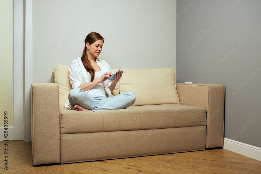 Smiling woman sitting on sofa using smartphone. Smiling woman sitting on sofa using smartphone.