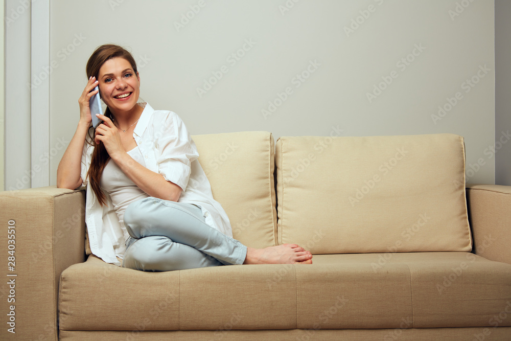 Woman sitting on sofa talking on mobile phone. Woman sitting on sofa talking on mobile phone.