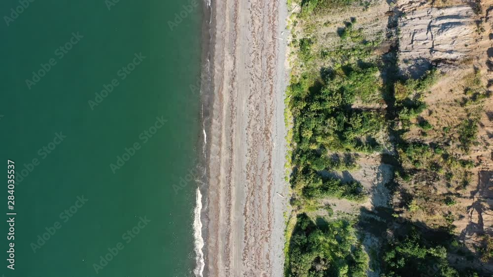 A straight line fly over a bluff and coastline as small waves from the Pacific Ocean hit the beach on a sunny, summer day in Alaska. A straight line fly over a bluff and coastline as small waves from the Pacific Ocean hit the beach on a sunny, summer day in Alaska.
