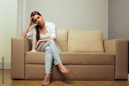 Tired woman in depression sitting on sofa