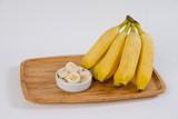 Banana em  prato de madeira no fundo branco