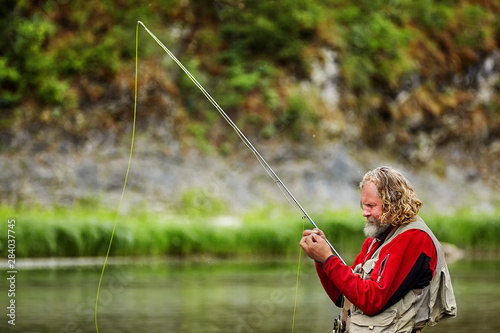 Fly fishing in water by mature man.