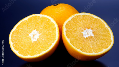 Citrus fruit. Cut and whole orange on dark background