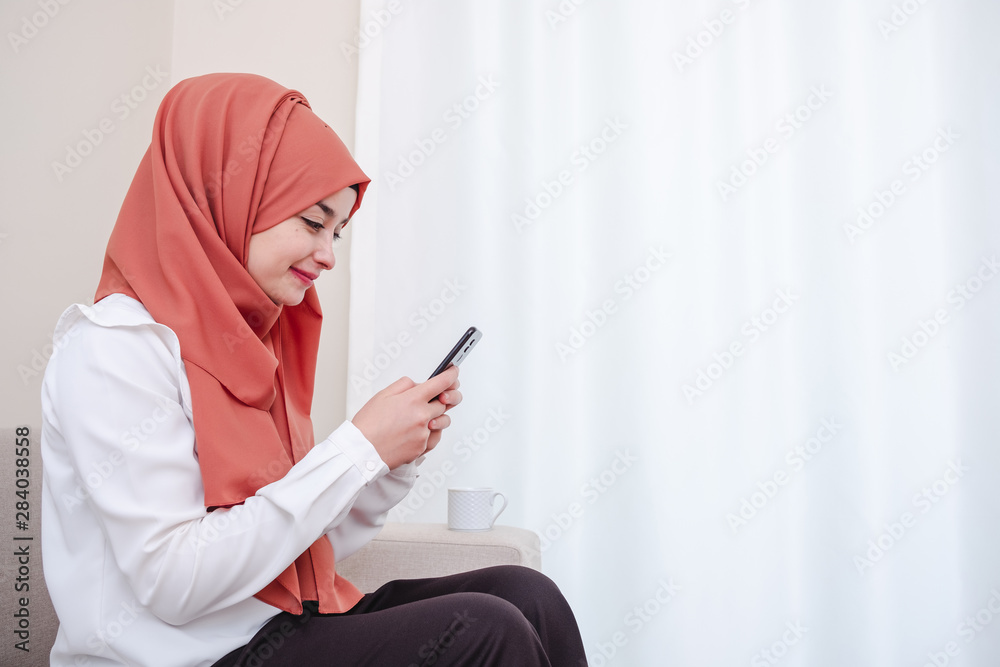 Muslim girl use smart mobile phone, hijab girl typing message at home Muslim girl use smart mobile phone, hijab girl typing message at home