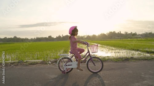 happy kid girl riding her bicycle outdoor during sunset photo