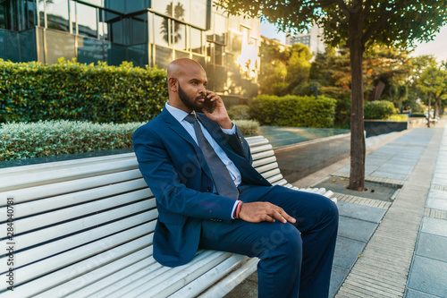 Indian businessman holding mobile phone wearing blue suit and using modern smartphone near office. Business concept