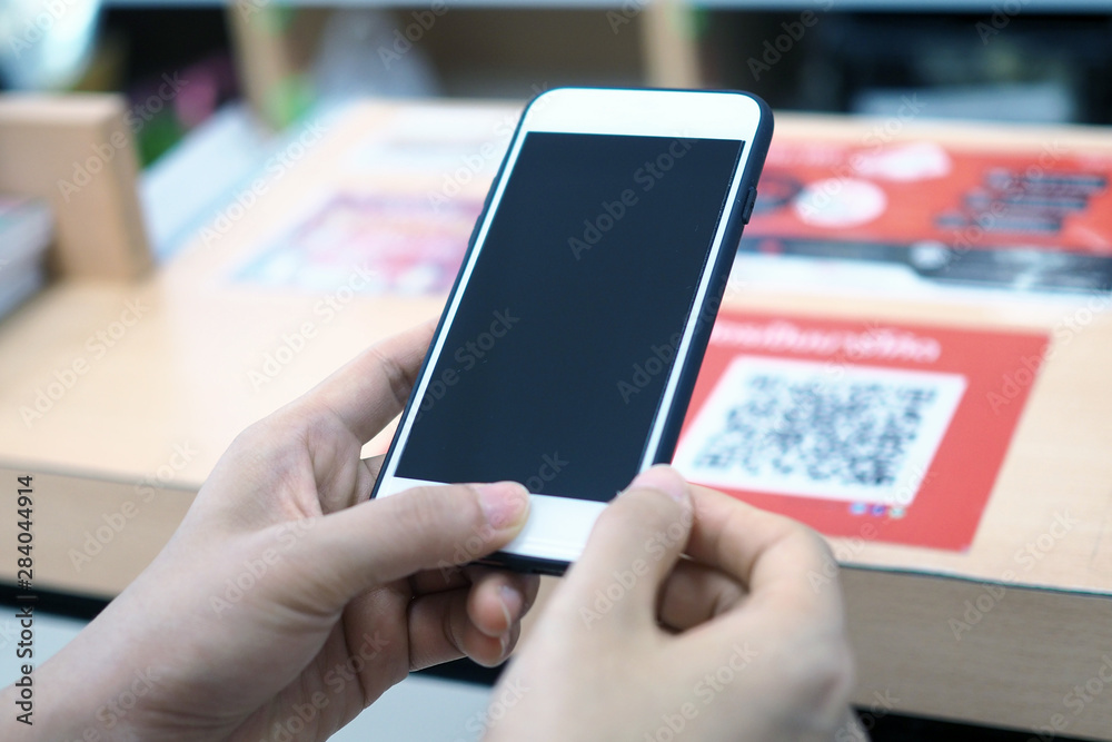 Hands use the phone to scan the QR code to receive discounts on purchases in the department store.