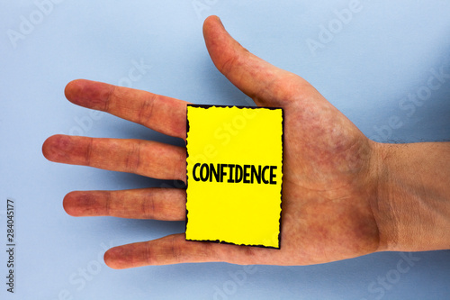 Handwriting text Confidence. Concept meaning Never ever doubting your worth, inspire and transform yourself written Yellow Sticky Note Paper placed Hand the plain background. photo