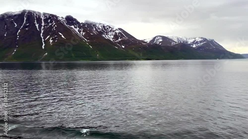 North Cape Norway Honningsvåg midnight sun above the Arctic Circle in Summer, heading north through fjords on ocean inlet from cruise ship  1080p. Near northernmost spot in Europe. photo