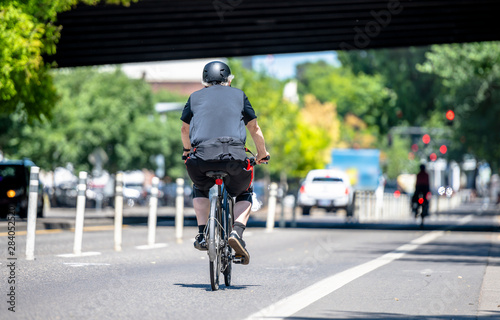 An elderly man rides a bicycle on a dedicated bike path along a city street © vit
