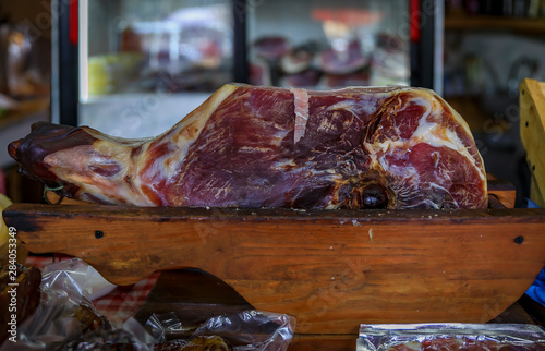 Whole bone-in ham leg of Montenegrin Njeguski prsut cured ham and sliced packaged meat at a market in Kotor Montenegro photo