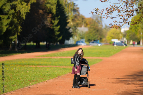 Mom walks with a stroller. A young mother enjoys the gardens when her little child is resting in her pram.