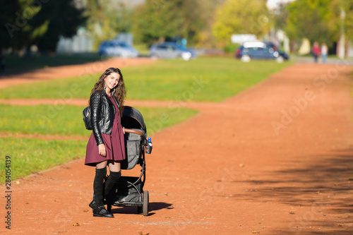 Mom walks with a stroller. A young mother enjoys the gardens when her little child is resting in her pram.