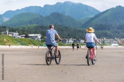 Mature couple rides bikes along the Pacific Ocean