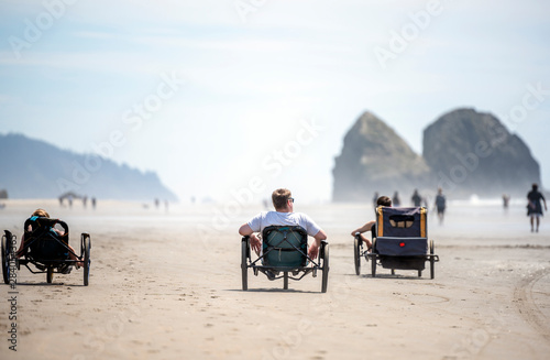People actively relax riding tricycles enjoying the fresh sea air on the Pacific Ocean